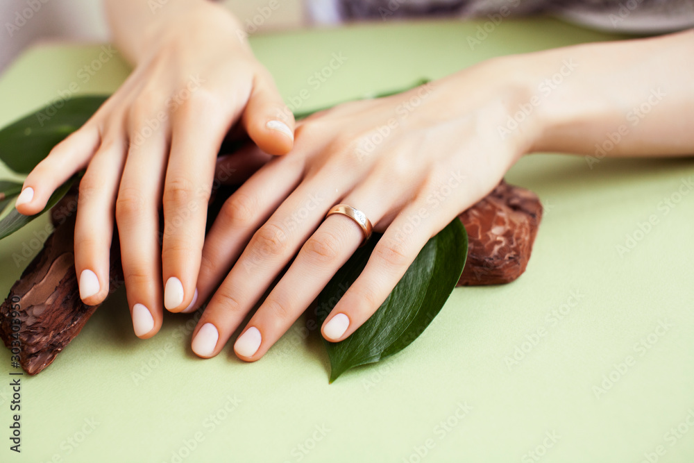 pretty perfect woman hands with white manicure and green leaf on colorful background with wood, spa cosmetic concept - obrazy, fototapety, plakaty 