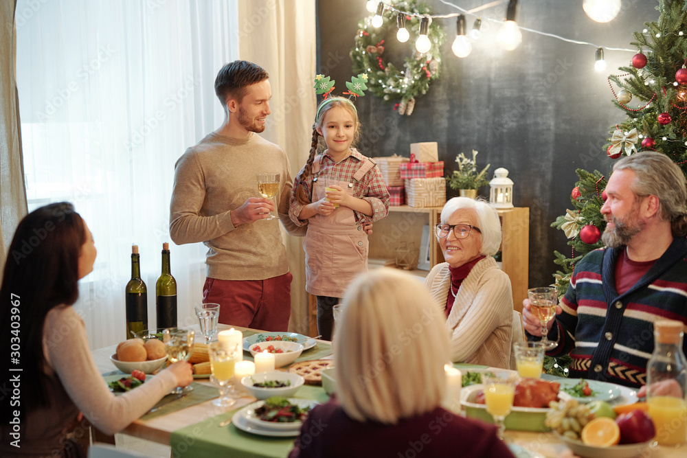 Φωτογραφία Young man and his daughter standing by served table in front of rest of family
