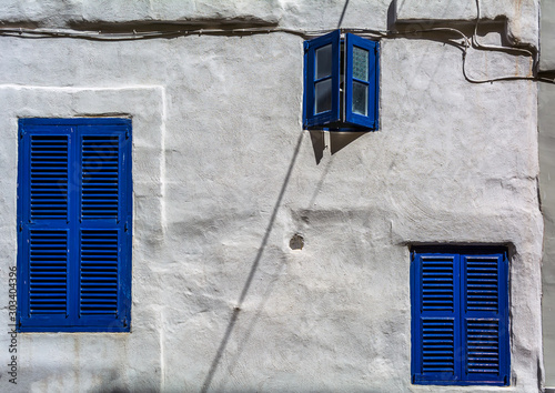 Three windows with navy blue shutters in white stone wall in Cospicua, Malta. Authentic Maltese urban scene. photo