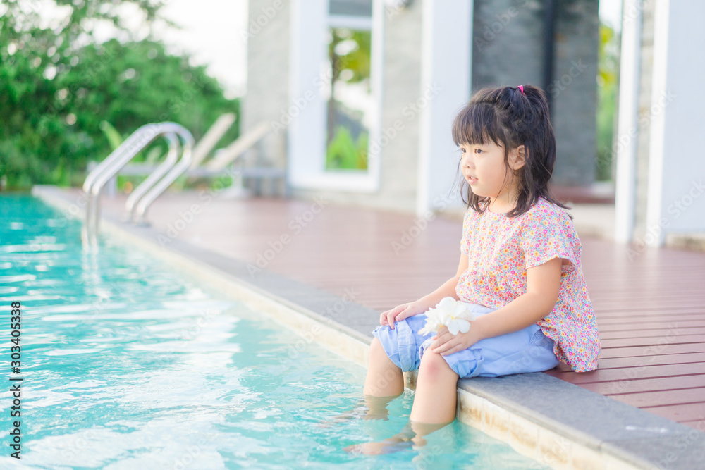 5 years old.Little asian girl sitting near swimming pool alone.