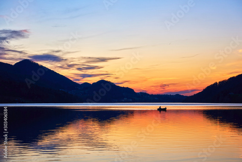 Lone fisherman catches fish on the lake Fuschl. Austrian Alps, Salzburg region