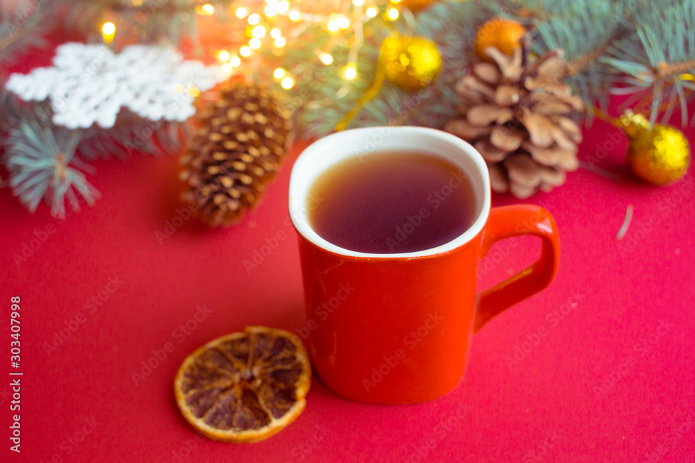red cup with hot tea on a red background with dried orange and cones. Christmas card. red cup with hot tea on a red background with dried orange and cones. Christmas card.
