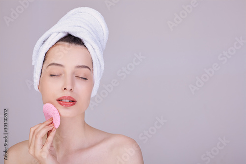 A young woman in a towel after a shower holds a toothbrush