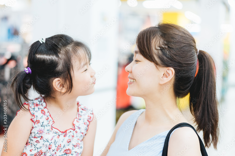 Laughing attractive asian mother and her cute little asian daughter in a supermarket.Mother and Daughter showing front teeth with big smile and laughing.Sale consumerism, Lifestyle, Dentistry Concept.