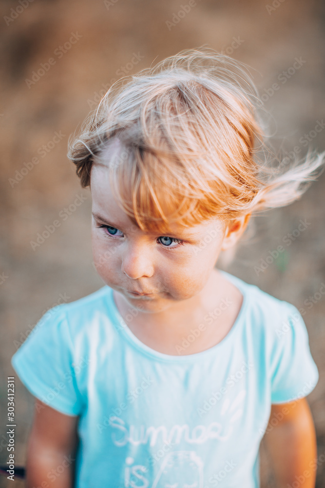 Close up portrait of little blonde girl with blue eyes outside with tousled hair and dirty face. Childhood in the country. Summer evening. Close up portrait of little blonde girl with blue eyes outside with tousled hair and dirty face. Childhood in the country. Summer evening.