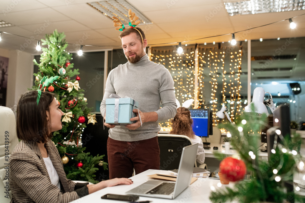 Φωτογραφία Young businessman with xmas headband giving present to one of colleagues