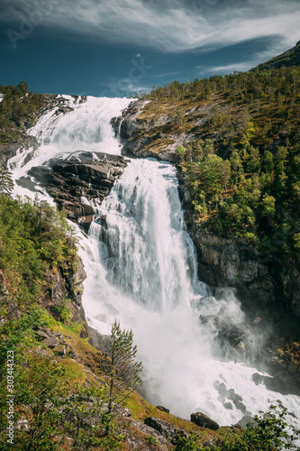 Kinsarvik, Hordaland, Norway. Waterfall Nyastolfossen In Hardangervidda Mountain Plateau. Nyastolsfossen in Spring Sunny Day. Height Of 115 m. Norwegian Landmark And Popular Destination