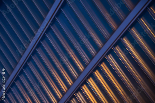 the metal facade of an industrial building illuminated by street lighting; abstract artistic background, diagonal lines pattern, blue and orange colors