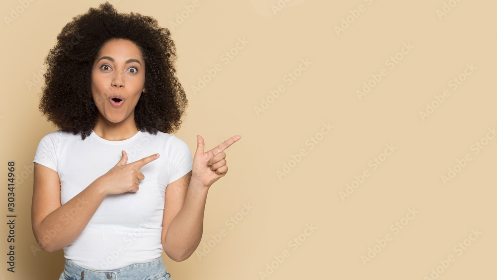 Surprised African American female pointing fingers to copy space - obrazy, fototapety, plakaty 