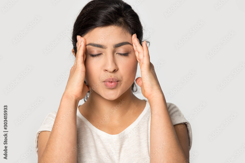 Stressed Indian girl massaging temples close up, suffering from headache Stressed Indian girl massaging temples close up, suffering from headache