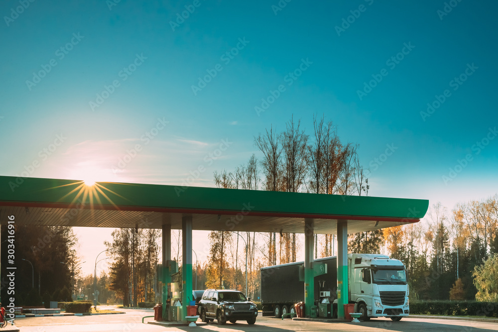 Car And Truck Tractor Unit, Prime Mover, Refuel At Gas And Oil Station In Sunny Autumn Day Car And Truck Tractor Unit, Prime Mover, Refuel At Gas And Oil Station In Sunny Autumn Day