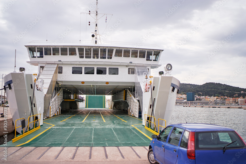 Ferryboat loading or unloading by a port pier. Concept of transportation and traveling. - obrazy, fototapety, plakaty 