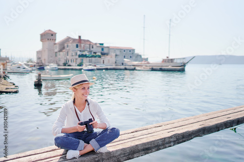 Tourism concept. Young traveling woman enjoying the view of Kastel Gomilica Castle sitting near the sea on Croatian coast. © luengo_ua