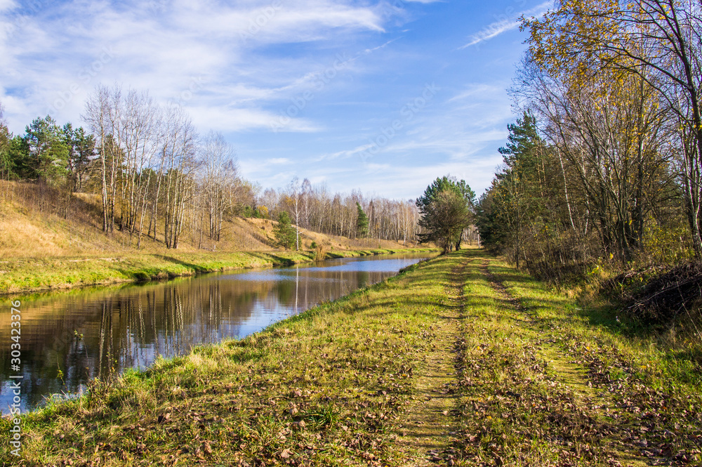 A forest river flows through a field and hills.