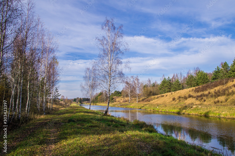 A forest river flows through a field and hills. A forest river flows through a field and hills.