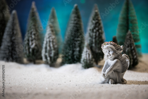 Little white guardian angel in snow. Festive background. Christmas decorations.