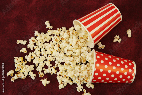 Two paper cup of popcorn and popcorn flies out on a red background with space for text and image. Flat Lay, Top View. Background, pattern, card. Cinema concept.