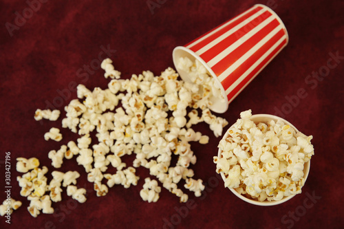 popcorn in a striped paper Cup and popcorn flies out on a red background with space for text. Flat Lay, Top View. Background, pattern, card. The concept of cinema.