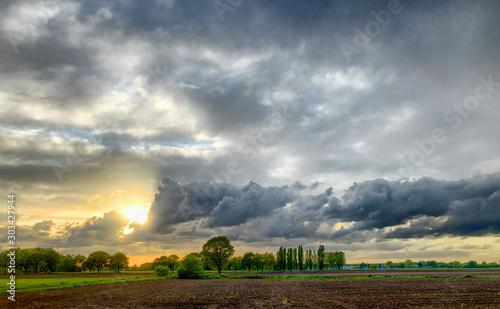 Colorful countryside sunrise or sunset over the agraric farmfields showing the dramatic colors and stormy clouds in the dark sky 