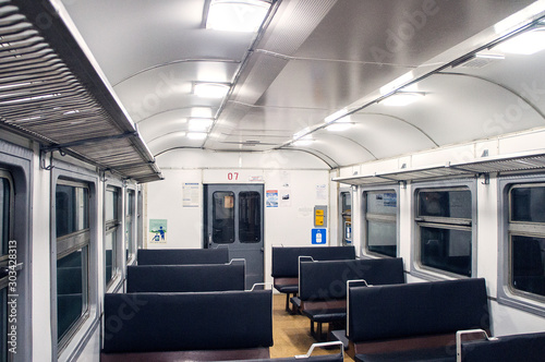 Interior of an empty train carriage with metal shelves and leather seats.