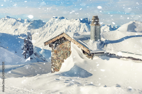Bild auf Leinwand Scenic Highland alpine old abandoned stone hut with chimney snowbound by thick snow layer after blizzard