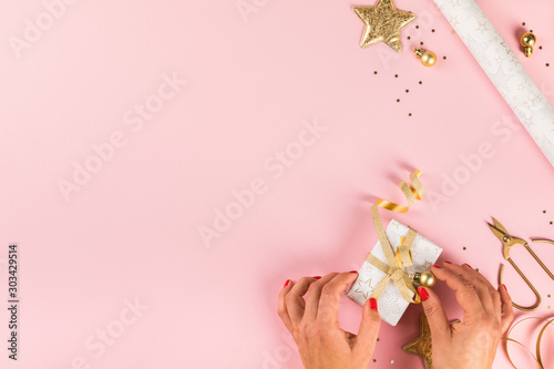 Fototapeta Naklejka Na Ścianę i Meble -  Preparing for Christmas holidays.Female Hands Wrapping Gift Box