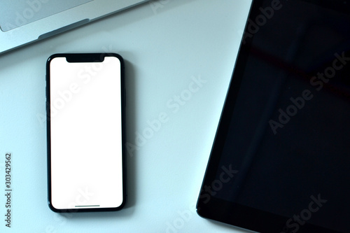 An Apple iPhone XS, a MacBook Pro and  an iPad on the office desk. It is common for people using Apple products both for mobile phones and laptops. The picture is shot in Istanbul,Turkey on 21/11/2018