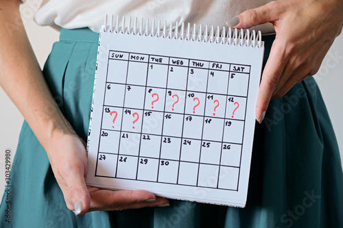Woman holding calender with marked missed period. Unwanted pregnancy, woman's health and delay in menstruation. photo