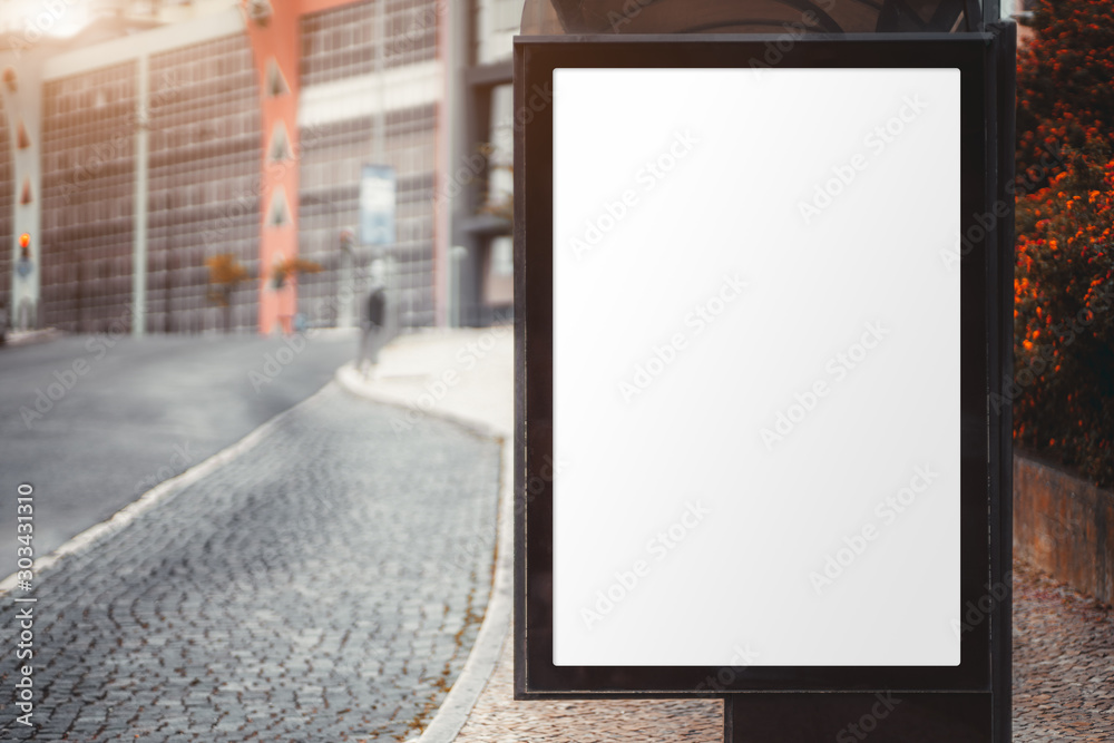 A city bus stop with an empty poster mock-up; template of an advertising banner on the stop of transport in a residential district; blank placeholder mockup on the pavement near an empty road A city bus stop with an empty poster mock-up; template of an advertising banner on the stop of transport in a residential district; blank placeholder mockup on the pavement near an empty road