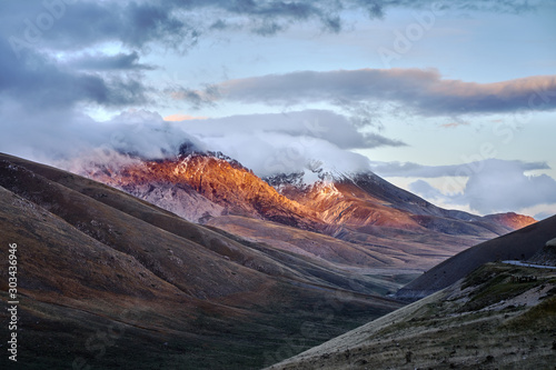 Italian Abruzzo Mountains Monte Camicia and Monte Prena covered by clouds at the evening with last sum beams.