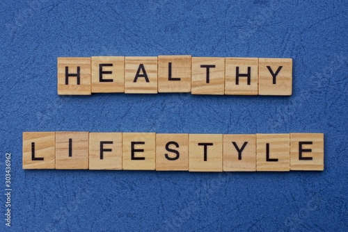 phrase healthy lifestyle made from brown wooden letters lies on a blue table