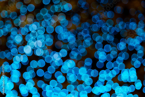 Illuminated Abstract round bright blue  bokeh on dark background. Colourful glitter bokeh from out of focus view of decoration bulbs.