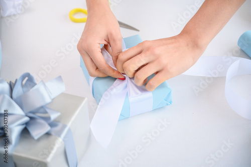 Woman wraps boxes with gifts for the new year. Female hands close-up. Prepares a surprise for Christmas. Wrapping paper and ribbon.