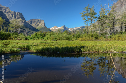 The pointed peak of Reynolds Mountain in the distance against a cloudless sky from an unnamed pond near St. Mary Lake, Glacier-Waterton International Peace Park (Glacier National Park), Montana, USA photo