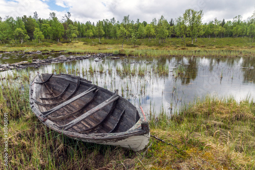 Old and weathered wooden boat wreck  laying on the ground in beautiful norwegian landscape with mountains in the background. Rustic and weathered concept.