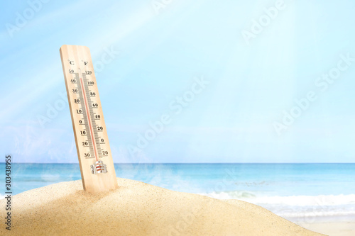 Thermometer measuring the temperature on the beach with a blue sky background photo