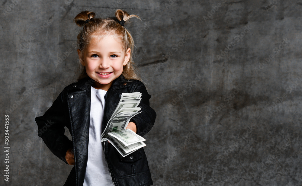 Happy smiling rich kid girl millionaire give and hold bundle of money euro hundreds dollars cash bills in hand Happy smiling rich kid girl millionaire give and hold bundle of money euro hundreds dollars cash bills in hand