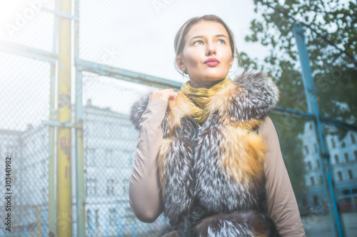 Beautiful caucasian girl  in winter clothes walk on the street, in a urban background, with autumanl foliage and a confident expression photo