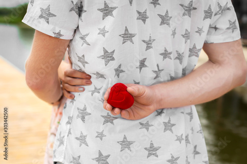 The guy wants to make an extension of his hand and heart to his beloved girlfriend. He hides a box with a wedding ring behind his back. The surprise that every girl is waiting for