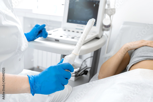 A gynecologist sets up an ultrasound machine to diagnose a patient who is lying on a couch. A transvaginal ultrasound scanner of the internal organs of the pelvis. Female health concept photo