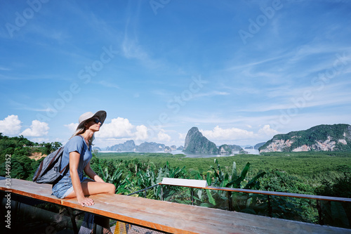 Traveling by Thailand. Young tourist woman enjoying wonderful view of Phang Nga bay with rock islands. © luengo_ua