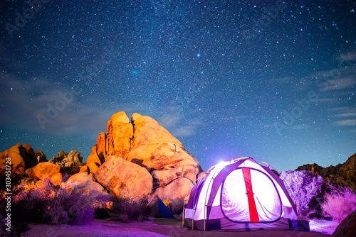 Illuminated Tent Next to Sandstone Beneath Starry Night Sky - Wide Angle