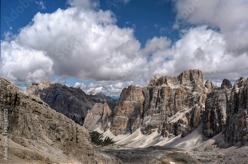 Scenic view in Italian Dolomites mountains. Rocks and peaks under blue sky with white puffy clouds. Falzarego Pass.  Cortina D'Amprezzo. South Tyrol. Italy. © aquamarine4