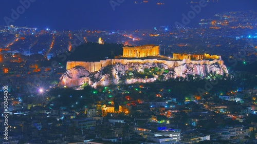 Cityscape of Athens with illuminated Acropolis hill, Pathenon and Herodium construction and sea at night. Athens skyline at night viewed from mount Lykavitos with Acropolis, Greece. Shot in dusk.