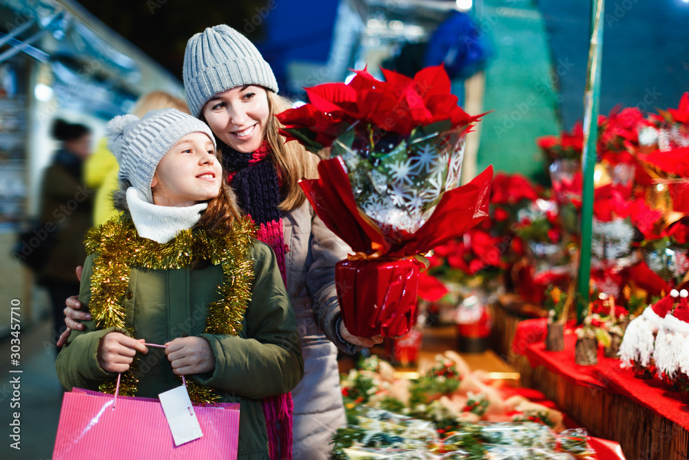 Φωτογραφία Young girl and her mother are buying Christmas ornamentals in the market outdoor