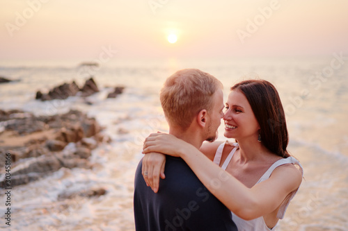 Romantic vacation. Love and tenderness. Young loving couple kissing and embracing on the sea sand and rock beach. © luengo_ua
