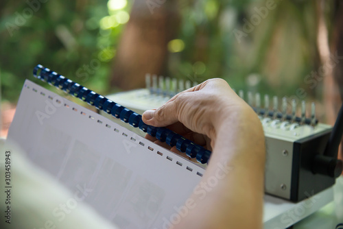 Man making report using comb binding machine - people working with stationary tools concept