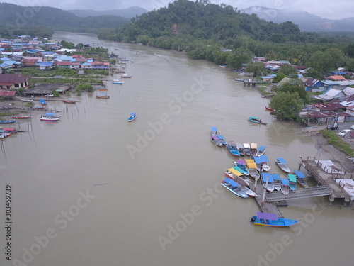 Kuching, Sarawak / Malaysia - November 18 2019:  The scenery of a traditional fishing village at Kuching, Sarawak, Malaysia. With the fishing boats along the Sarawak River and the villages on both sid photo