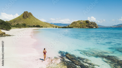 Woman walking and enjoying empty paradise tropical beach with mountain view. Nobody around. Aerial view of Padar island Pink Beach. Panoramic photo.