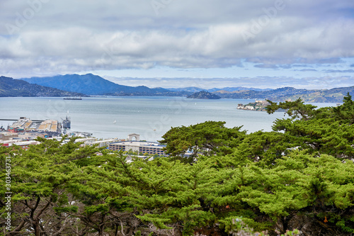San Francisco, CA, USA - May 15, 2018: View of the San Francisco Bay from the observation deck of Columbus. Rolling hills, cloudy, functioning cargo piers